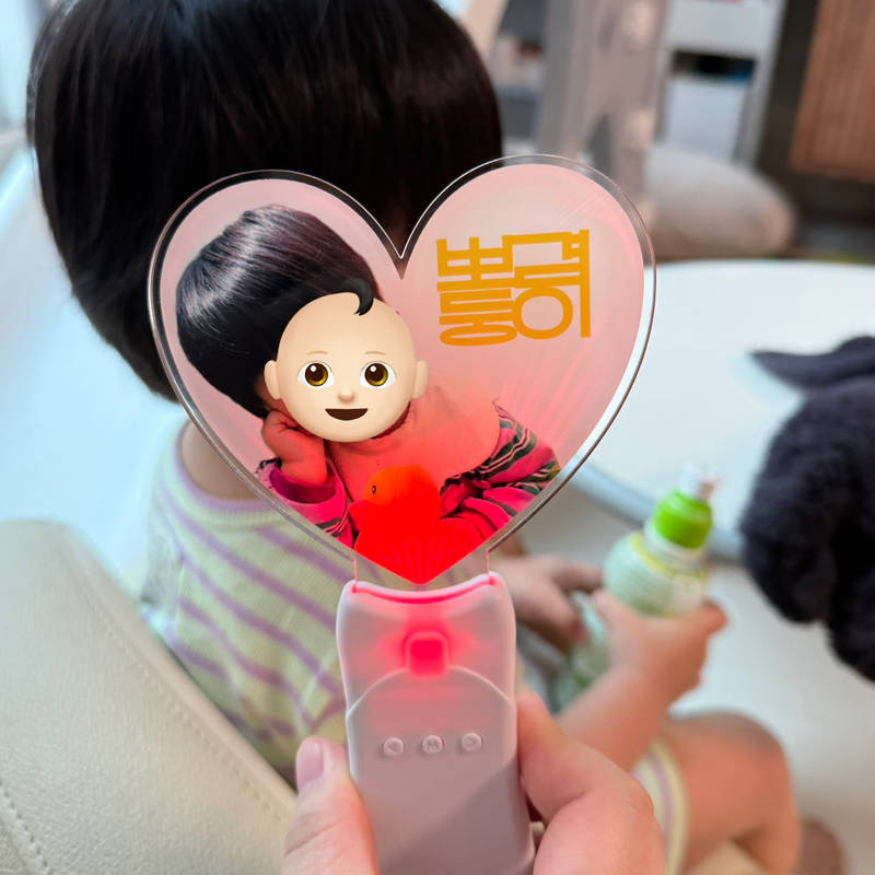하트 LED 응원봉 (핸드 스틱) 10.4 x 19.1 cm 구매 제작 후기 친한 언니네 아기 얼굴로 만든 건데, 하트 모양 안에 해맑게 웃고 있는 사진이 들어가 있으니까 진짜 아이돌 응원봉 부럽지 않더라고요. 
뒷면은 좌우반전되어 들어가 있어서 더더욱 퀄리티가 좋아보여요!

아기한테 쥐어주니까 손잡이도 가벼워서 아이가 직접 들고 있어도 잘 어울리더라구요!

불빛도 들어오는 게 완전 관심 폭발 포인트!
버튼 누르면 컬러가 바뀌고 조명처럼 강하지 않고 딱 예쁜 분위기라서 아이도 좋아하고 어른들도 보기 좋더라고요. 실제로 밤에 살짝 켜놓고 사진 찍으니까 너무 예쁘게 나와서 다들 감탄했어요. 조작도 어렵지 않아서 아기가 버튼 누르며 신기해하는 모습이 너무 귀엽더라고요.

사실 처음엔 그냥 귀여운 소품일 줄 알았는데, 막상 보니까 감성도 있고, 선물로도 딱이에요. 아기 얼굴이 들어가 있으니까 세상에 하나밖에 없는 느낌이 들고, 가족들이랑 함께 응원하는 것도 하나의 추억이 되더라고요. 아이 있는 집에 이런 거 하나쯤 있으면 정말 분위기 확 살아나는 것 같아요.

선물해준 언니가 나중에 유치원 운동회나 행사때 꼭 들고 가서 흔들며 응원할거라고 너무 좋아했어요! 
건전지 포함되어있어서 별도로 사지 않아도 되니까 바로 쓸 수 있어서 좋았습니다. 
*직원이 실제 사용 후 작성한 리뷰입니다.- 마플 리얼 후기